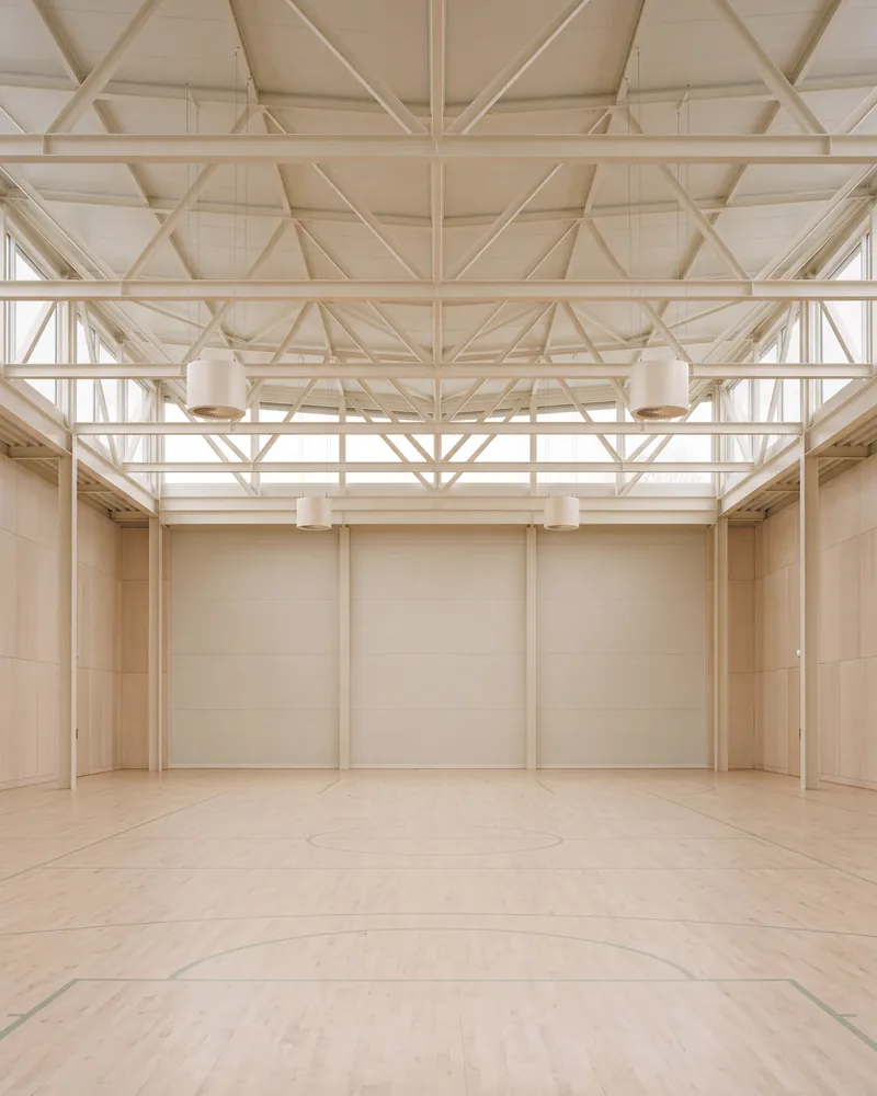 Gymnase au parquet clair avec déstratificateurs sous la charpente